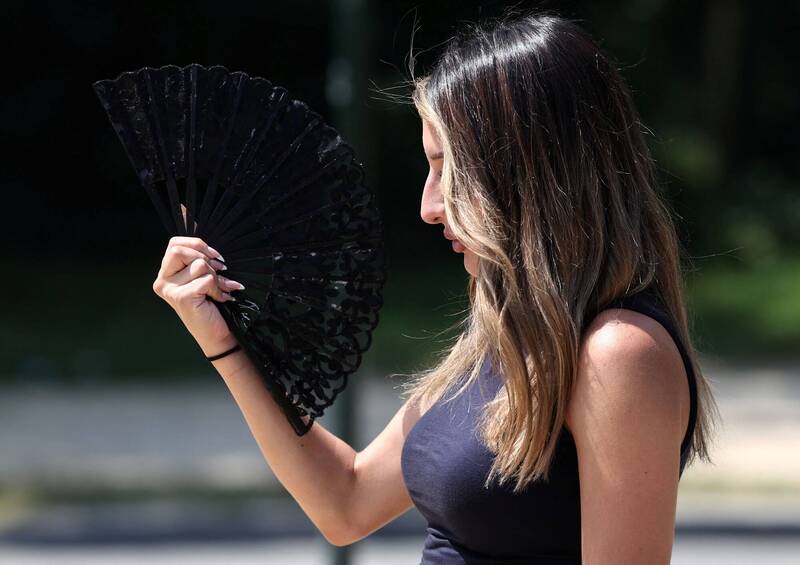 布鲁塞尔一名女子7月2日以折扇降温，反映欧洲多国正面临热浪侵袭与异常高温。（路透）