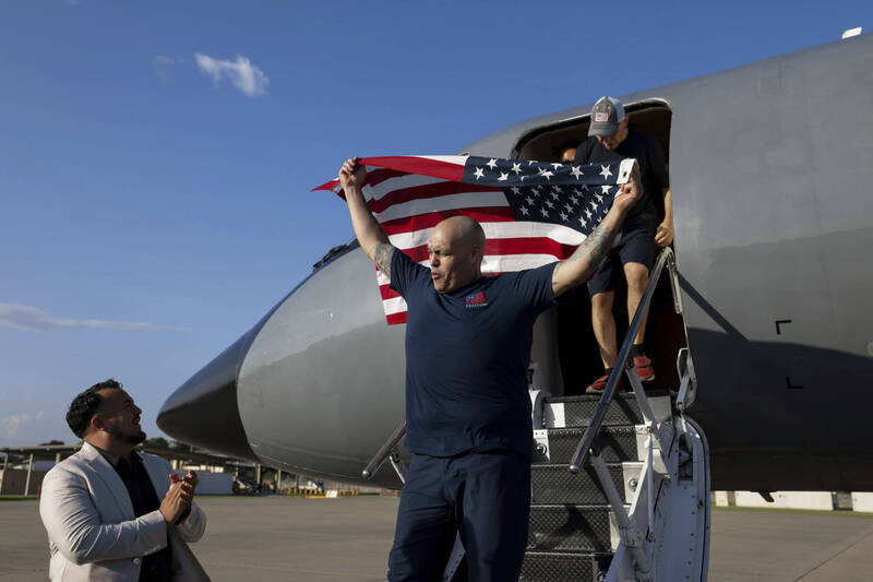 美國換回10名囚犯，獲釋其中一人到達機場後揮舞國旗。（美聯）