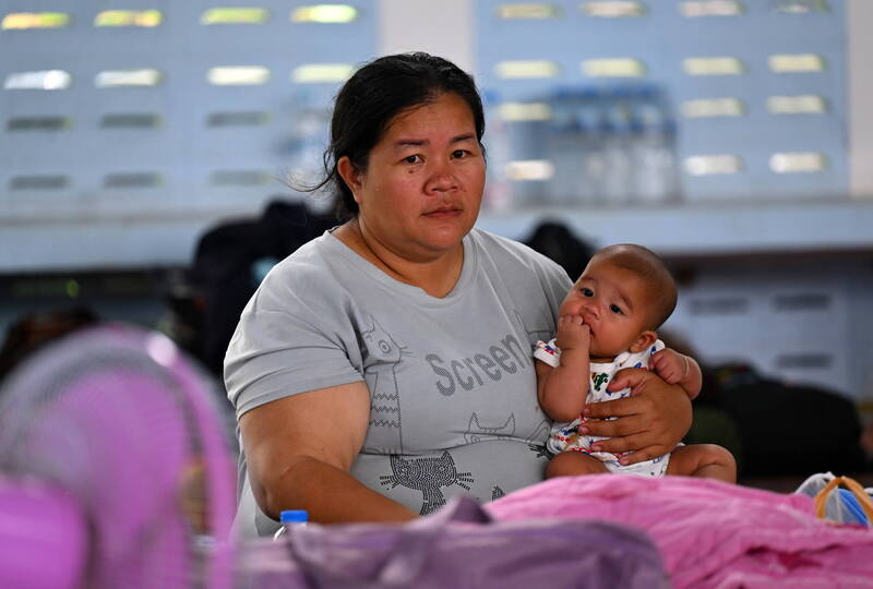 泰柬冲突已造成至少14死。图为在泰国疏散中心的妇女抱着婴儿。（欧新社）