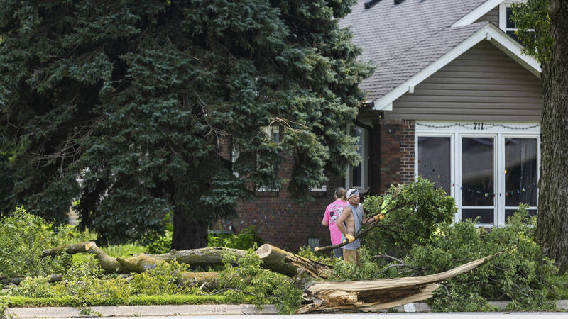 內布拉斯加州9日遭強風暴襲擊。圖為民眾清理倒塌樹木。（美聯社）